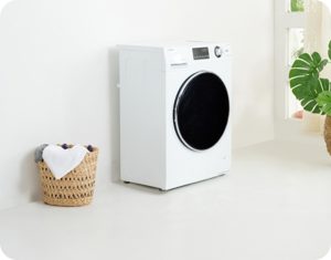 White front-load washing machine next to a wicker laundry basket with clothes.