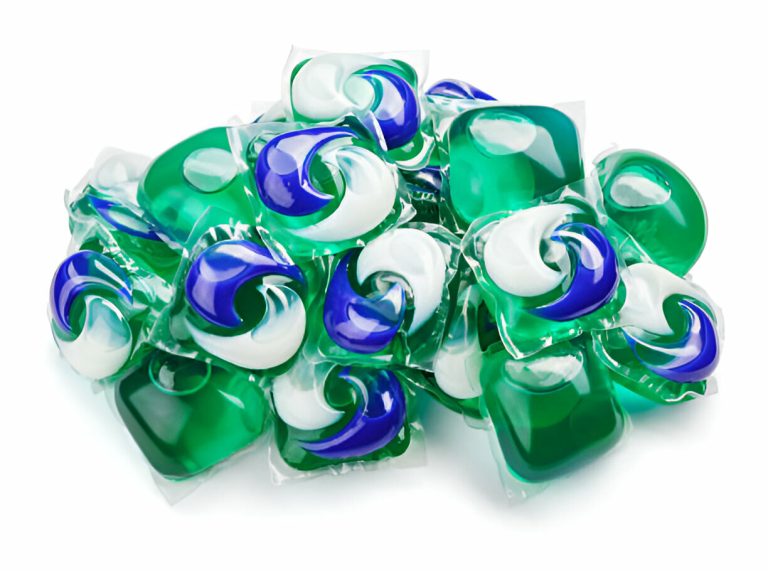 A pile of green, blue, and white laundry detergent pods on a white background.